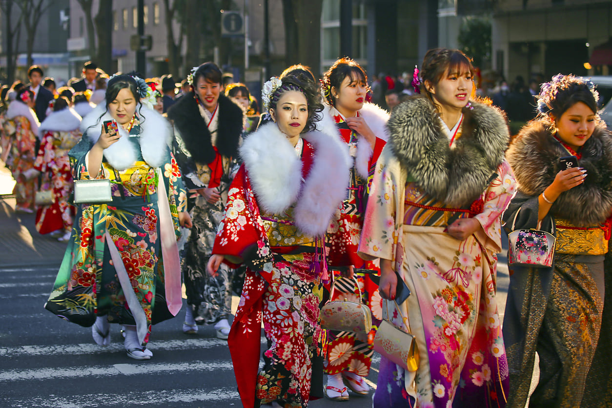 A group of young women in vibrant furisode kimonos walking down the street, capturing the festive and traditional spirit of Coming of Age Day.