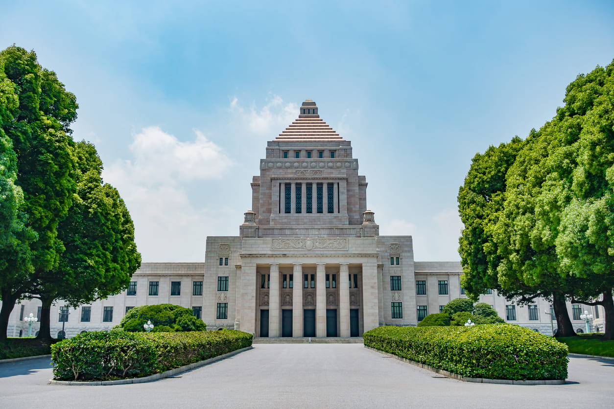 The National Diet Building is framed by lush greenery under a bright blue sky, highlighting its stately architecture and symbolic role in Japan’s democracy.