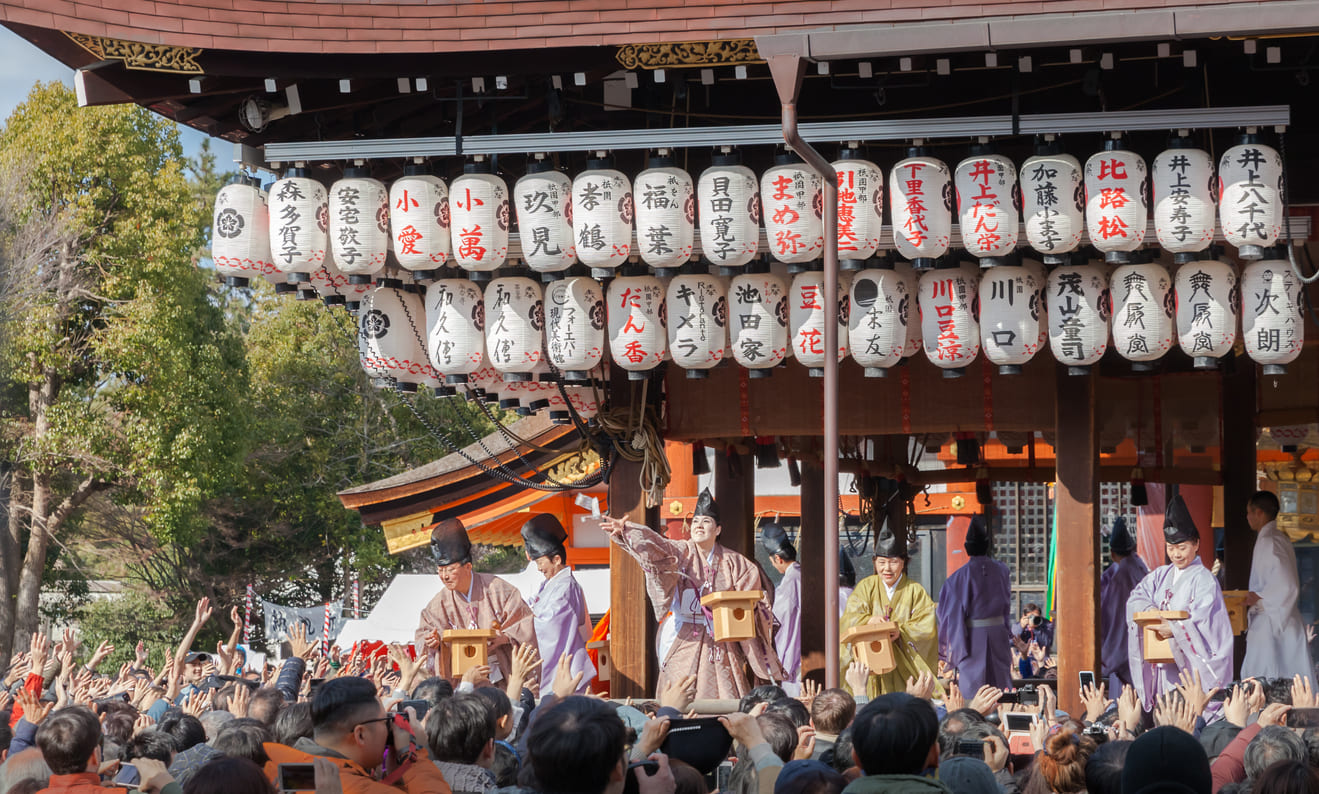 Shinto priests at Yasaka Shrine in Kyoto performing the Setsubun ritual, scattering soybeans to symbolically drive away oni and invite good fortune.