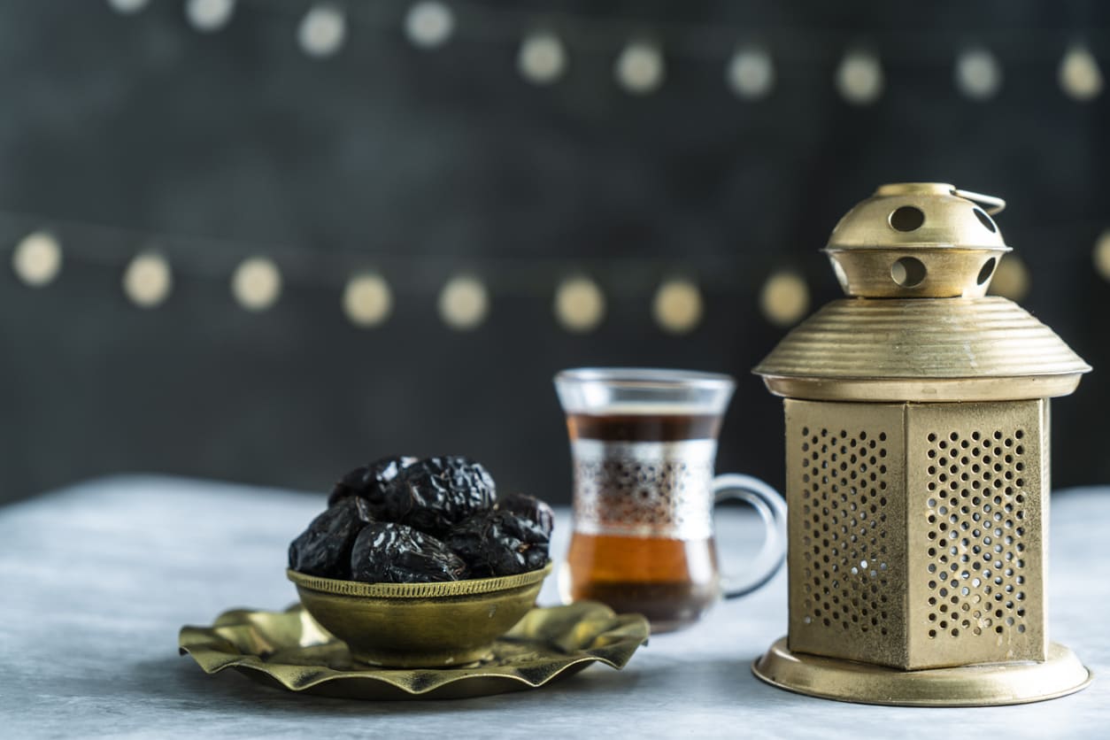A traditional Ramadan setting with a bowl of dates, a glass of tea, and a decorative lantern, capturing the essence of Awal Ramadan.