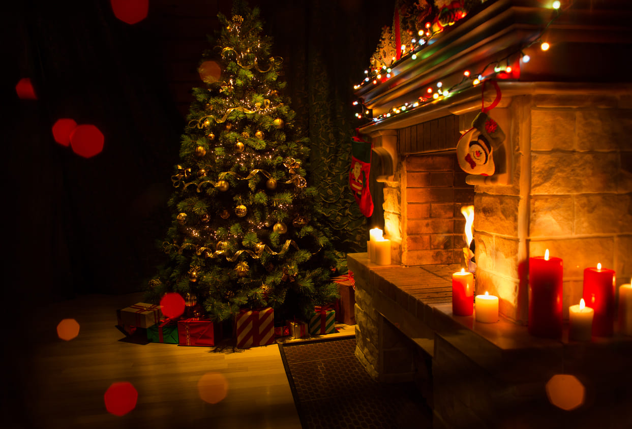 A beautifully decorated Christmas tree and a glowing fireplace create a warm and festive holiday atmosphere.