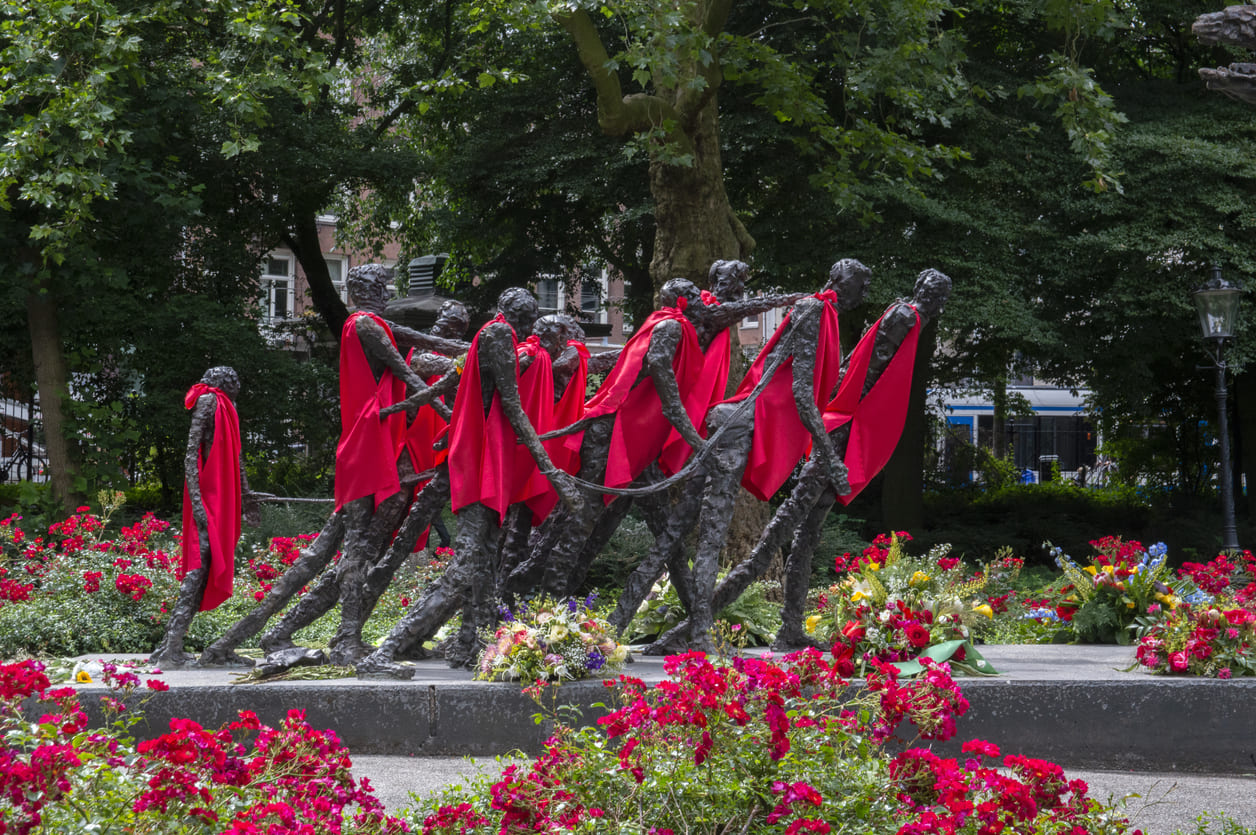 The National Slavery Monument in Amsterdam, surrounded by vibrant flowers, stands as a powerful symbol of freedom and remembrance during Keti Koti.