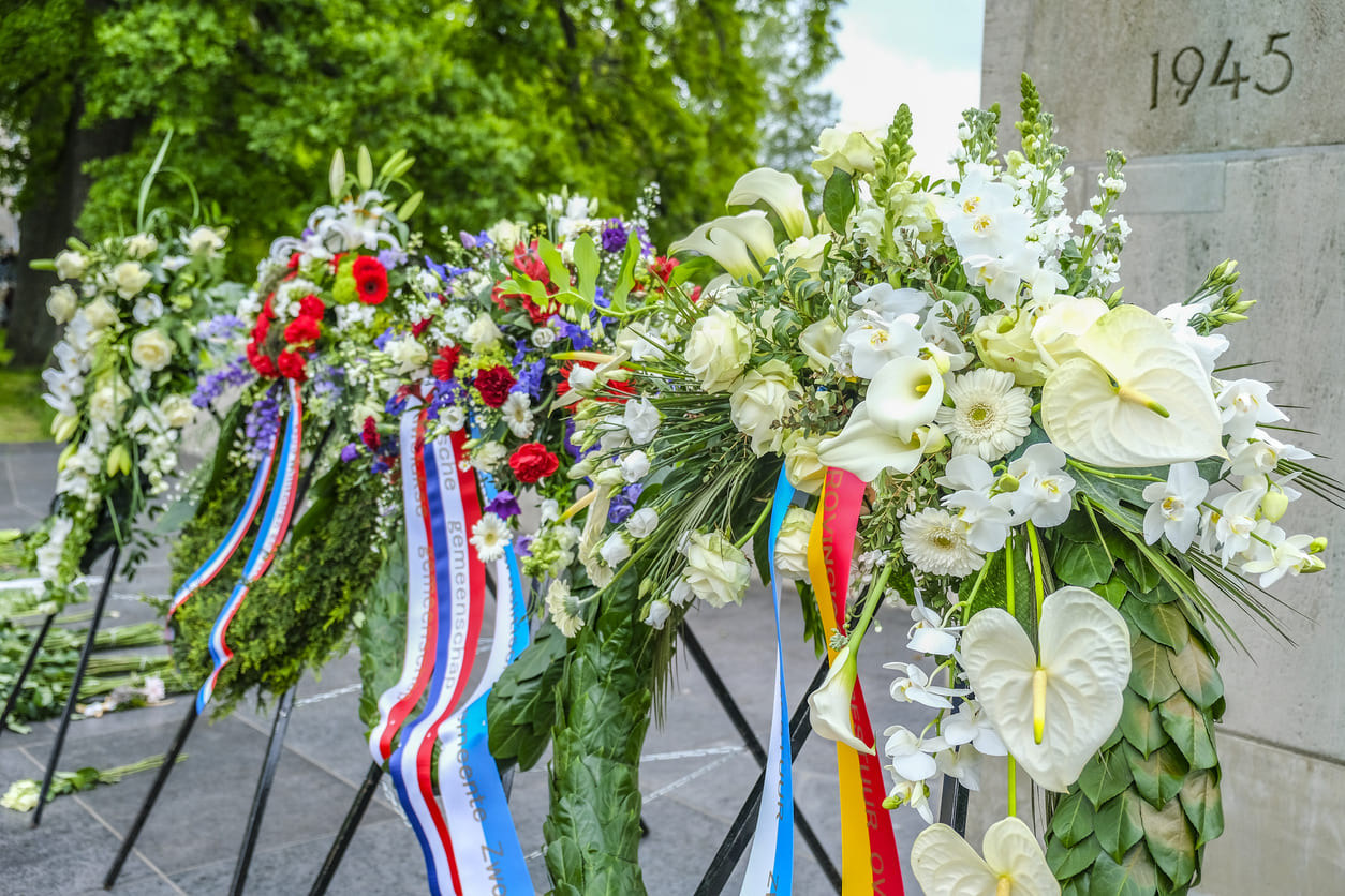 Floral wreaths with ribbons stand in solemn tribute, commemorating the fallen on Remembrance Day in the Netherlands.