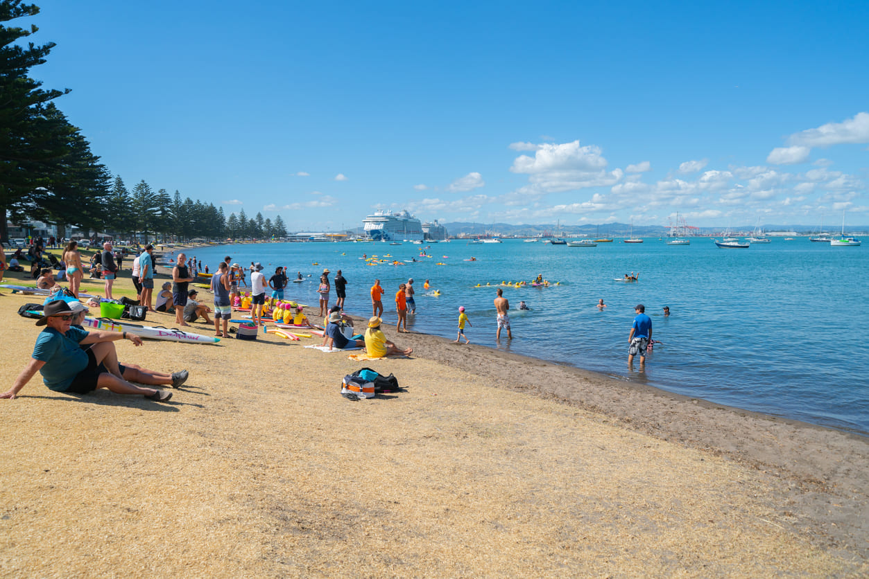 A sun-drenched beach bustling with families and friends, capturing the laid-back joy of Boxing Day in New Zealand.