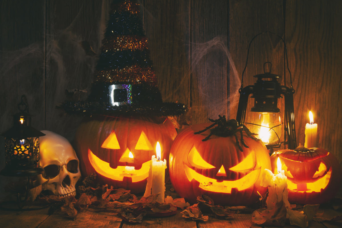 A warm, eerie display of glowing jack-o'-lanterns, candles, and spooky props capturing the playful spirit of Halloween.
