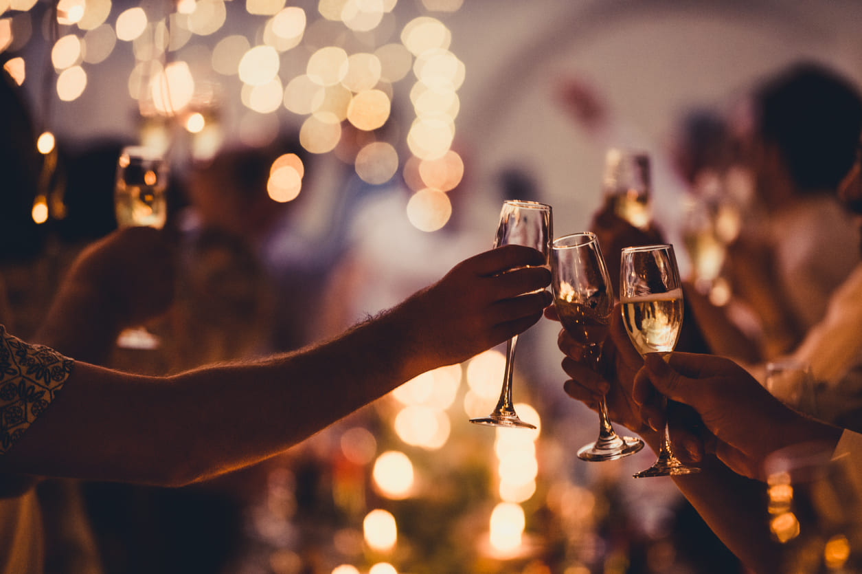 A close-up of hands raising sparkling glasses in a lively celebration, reflecting the warmth and festive spirit of New Year's Eve in New Zealand.