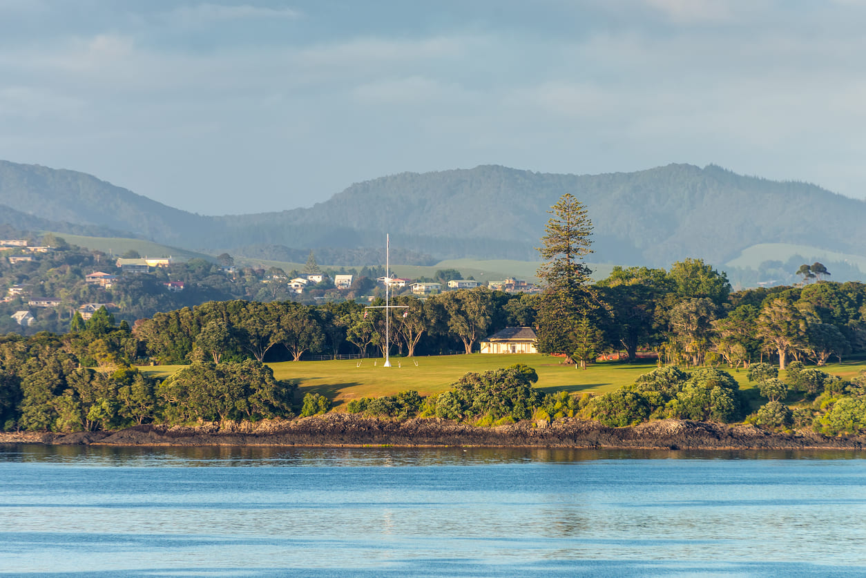 A scenic view of the historic Waitangi Treaty Grounds, surrounded by lush greenery, marking the birthplace of modern New Zealand.