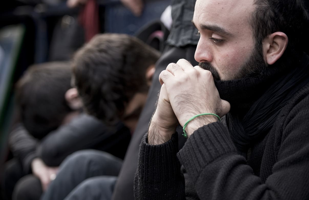 Individuals in a solemn and reflective state, symbolizing the grief and mourning observed during Ashura.