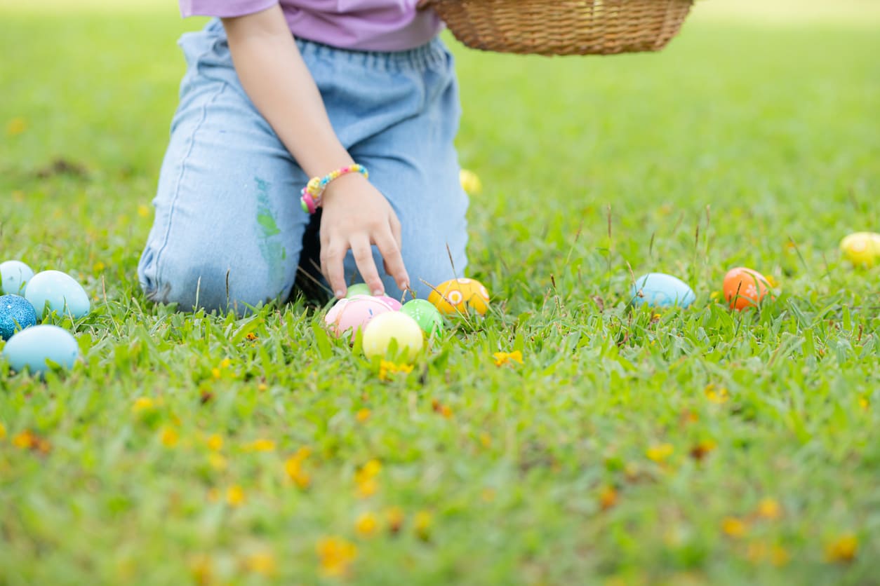 A child gathers colorful Easter eggs in a grassy field, symbolizing the festive spirit of Easter.