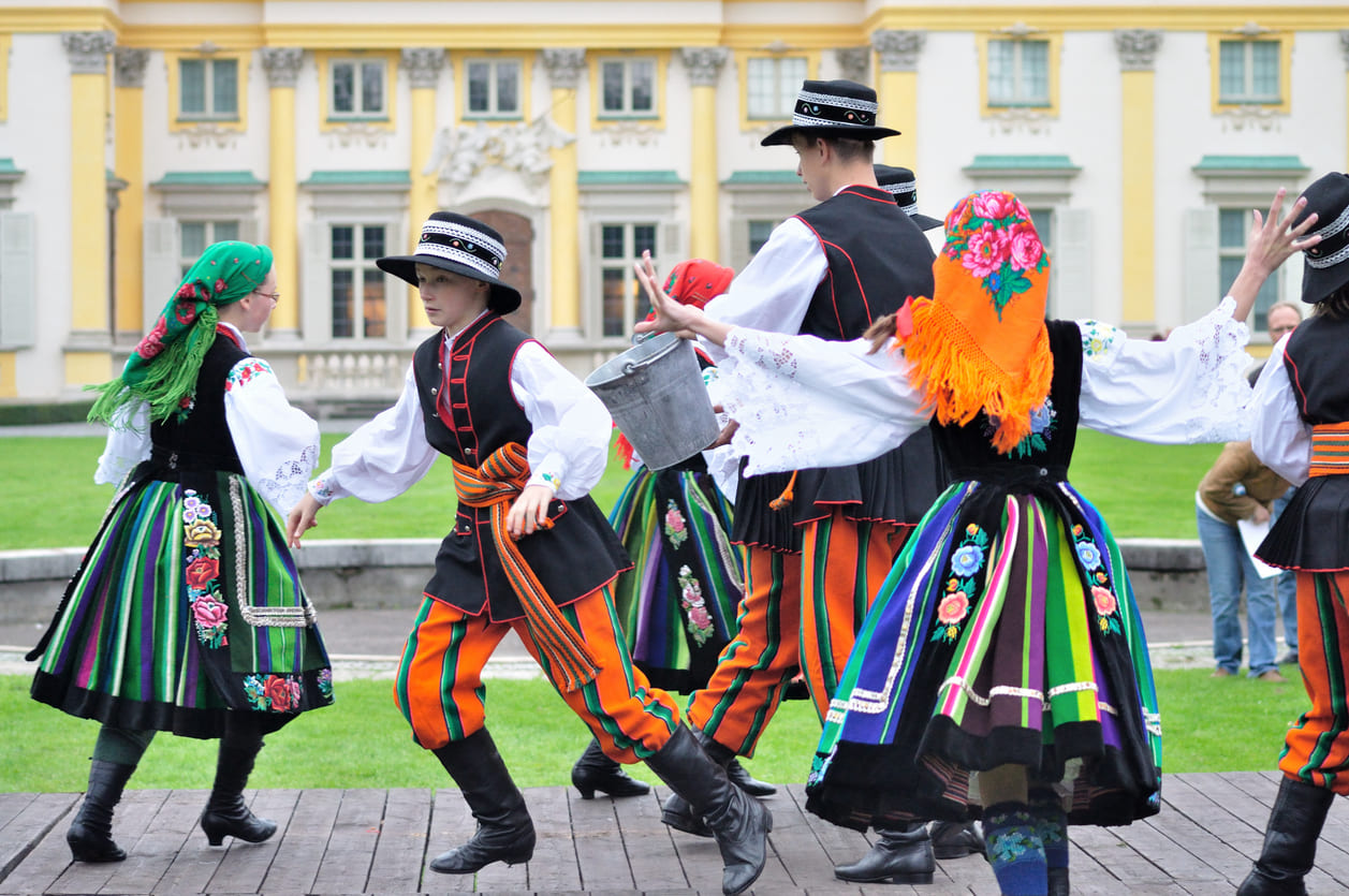 People dressed in colorful traditional Polish costumes, dancing during Easter Monday celebrations, embodying the lively spirit of Śmigus-Dyngus.