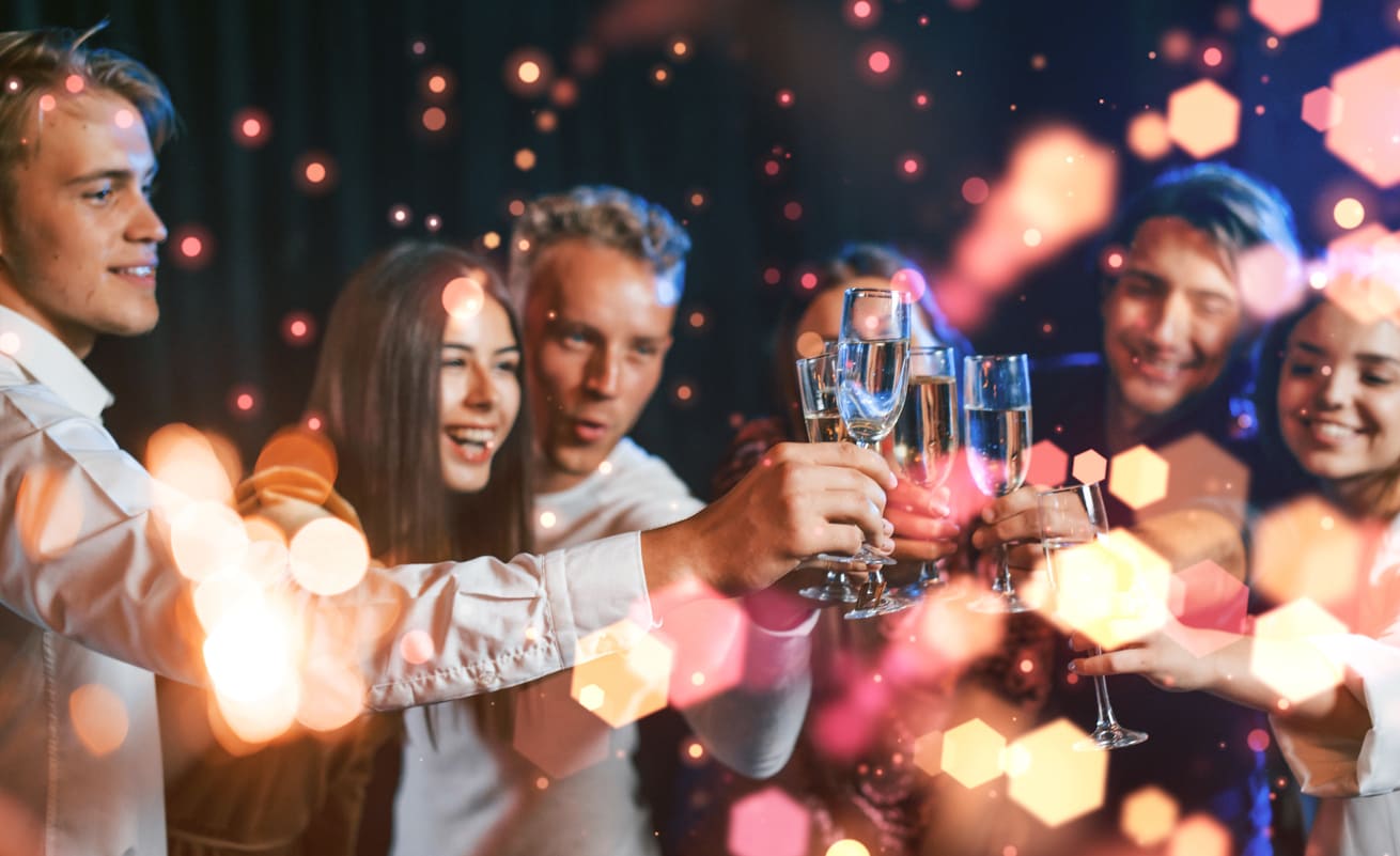 A group of friends celebrating New Year's Eve, raising champagne glasses in a lively atmosphere with sparkling lights.