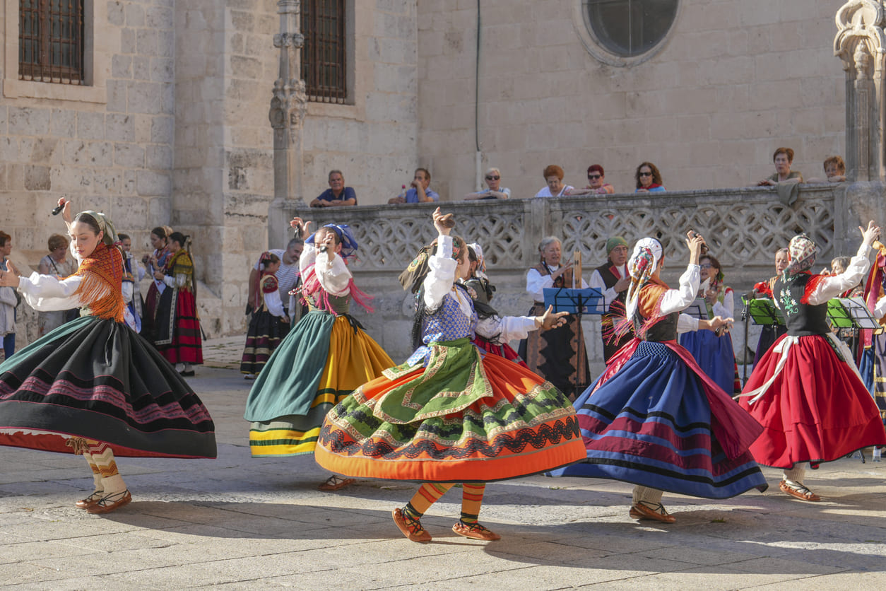 A vibrant scene of dancers in traditional Castilian attire gracefully performing the Jota Castellana, accompanied by live folk music in a historic setting.