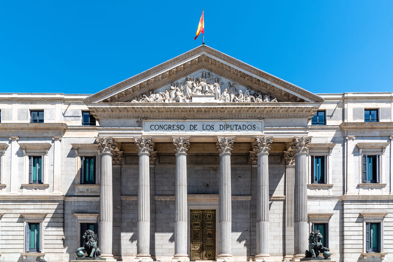 The Spanish Congress of Deputies building in Madrid, with the national flag waving above, symbolizing democracy and the celebration of Constitution Day in Spain.