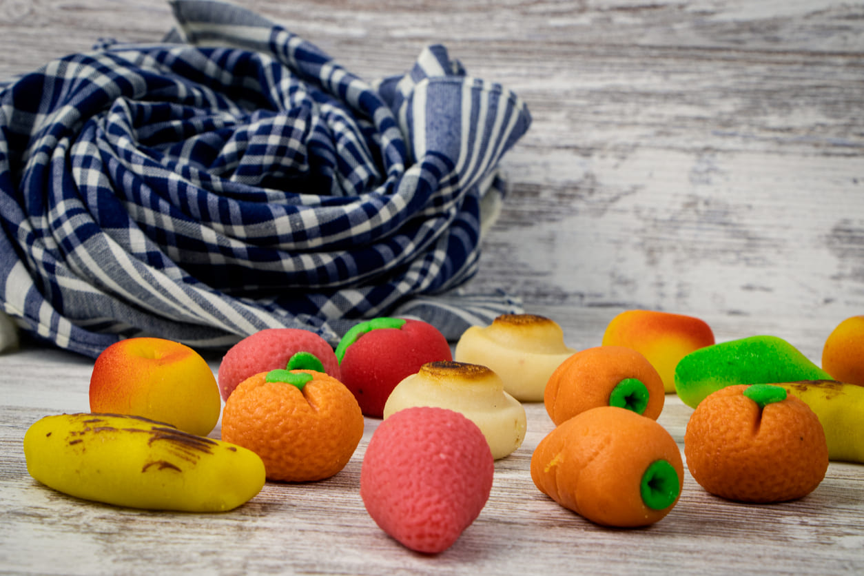 A colorful assortment of marzipan sweets shaped like fruits, traditionally wrapped in a handkerchief, symbolizing love and celebration on the Day of the Valencian Community.