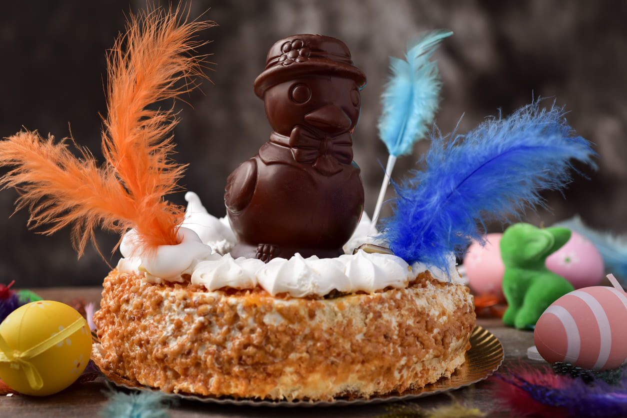 A beautifully decorated Mona de Pascua cake, featuring a chocolate figure and colorful feathers, symbolizes the sweet tradition of Easter Monday in Spain.