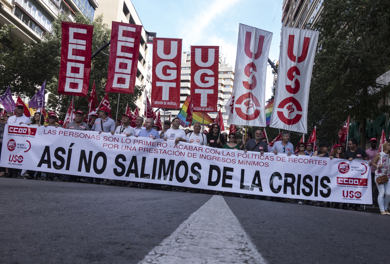 A Labor Day protest in Spain, featuring workers and labor unions marching with banners and flags, demanding better wages and social rights.