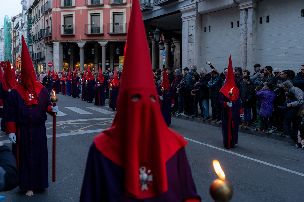 Hooded penitents dressed in traditional robes march through the streets during a Semana Santa procession, carrying torches in solemn observance of Maundy Thursday in Spain.