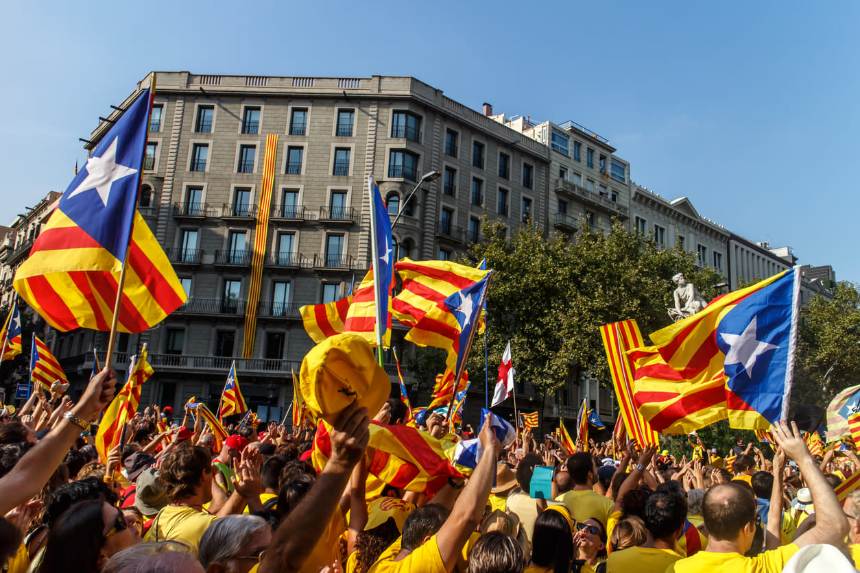 A lively crowd dressed in yellow and red waves Catalan independence flags (Estelades) in the streets, celebrating La Diada with passion and unity.