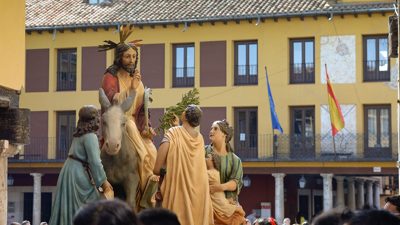 A religious float depicting Jesus' entry into Jerusalem, moves through a Spanish town during a Palm Sunday procession.