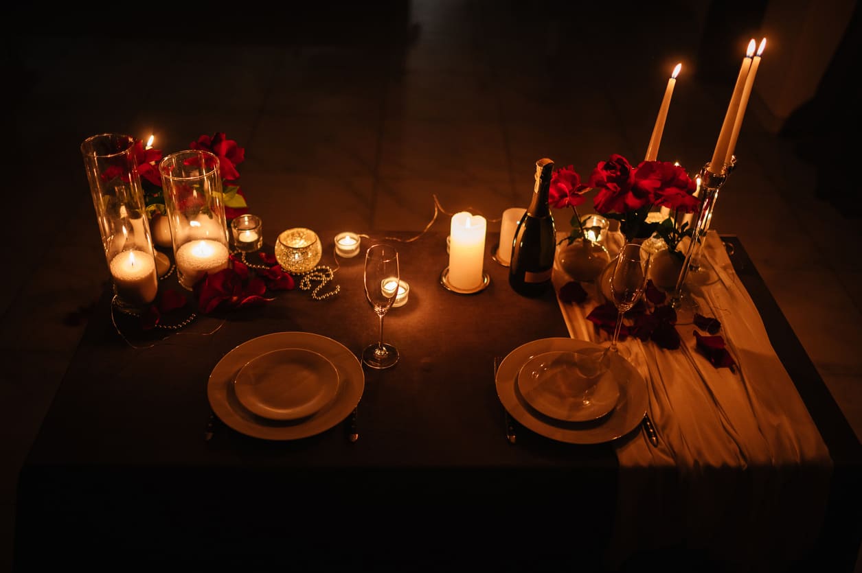 A beautifully arranged candlelit dinner table, adorned with red roses, champagne, and soft lighting, creating a romantic Valentine's Day ambiance.