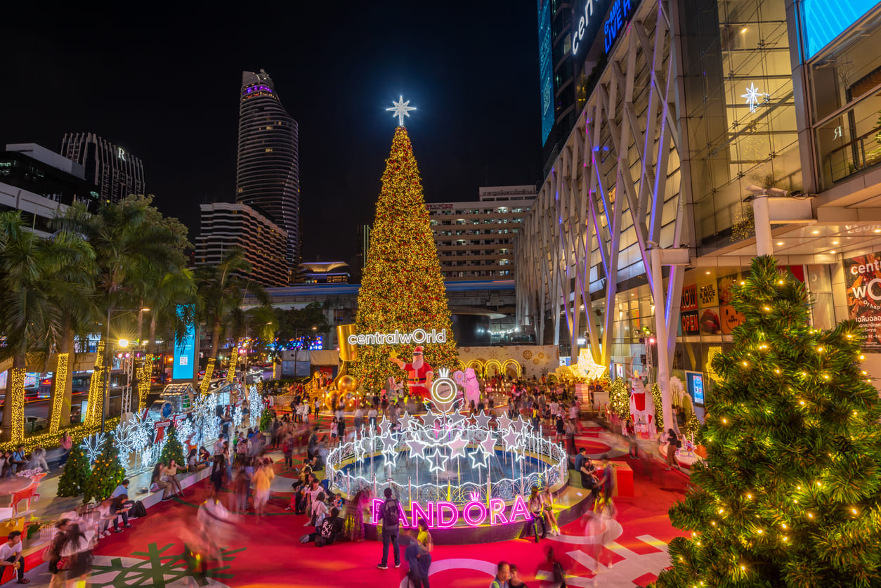 A brightly decorated Christmas tree and glowing lights create a festive scene at CentralWorld, attracting cheerful crowds on Christmas Day.