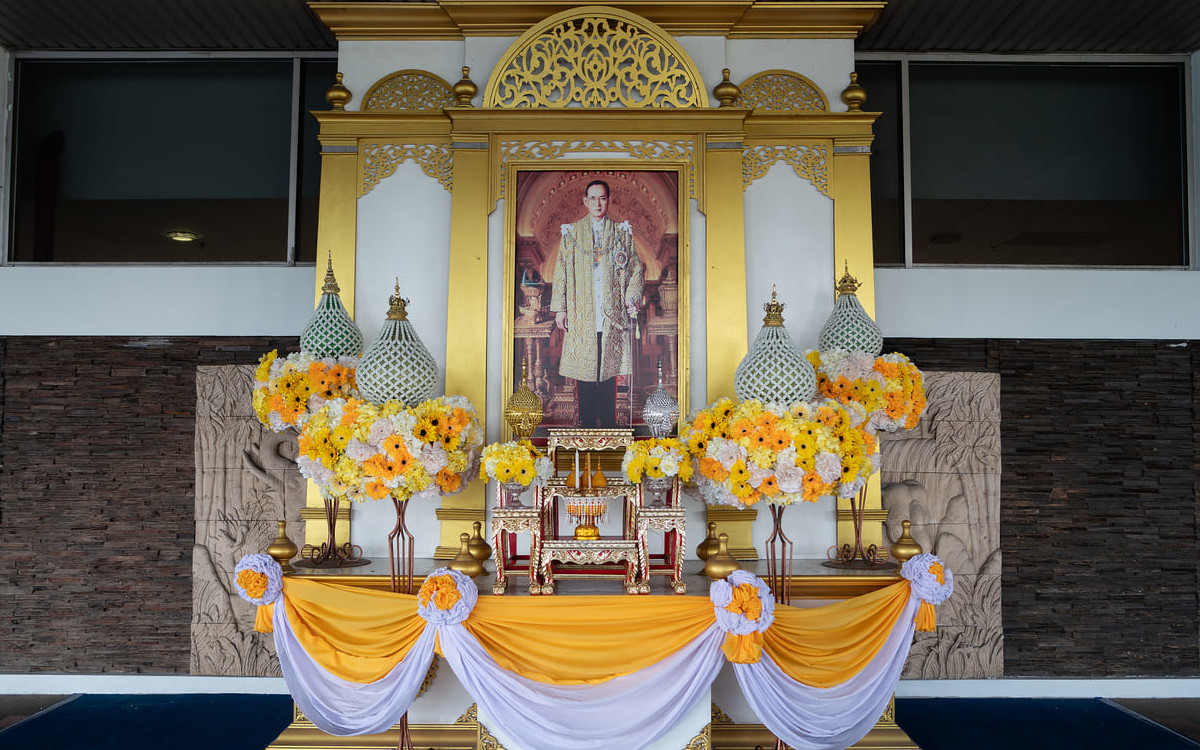 A beautifully decorated display with King Bhumibol's portrait and yellow flowers at Chiang Mai International Airport, symbolizing national respect on his Birthday and Father's Day.