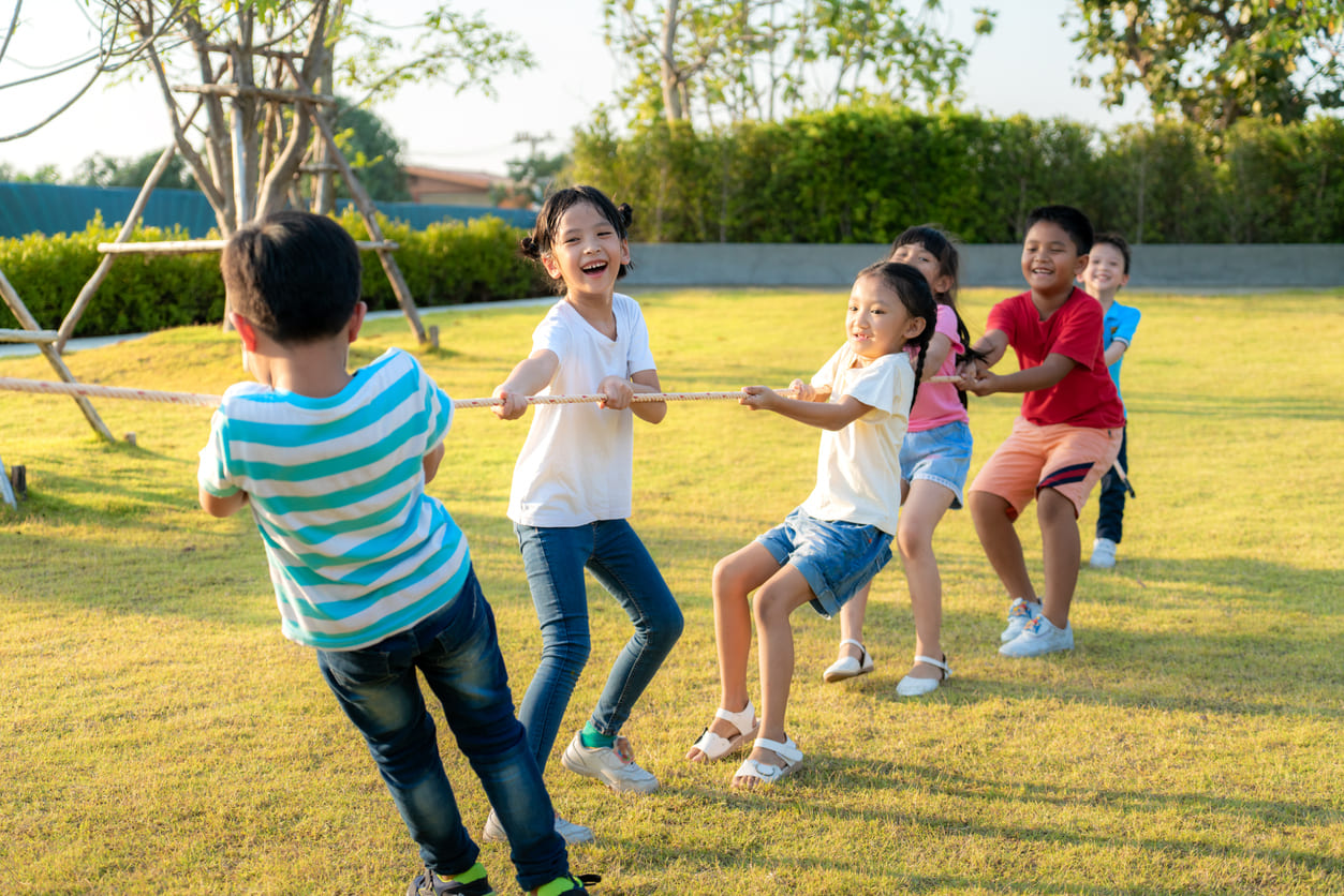 A group of children playing tug-of-war outdoors, reflecting the playful and energetic atmosphere of National Children's Day celebrations.