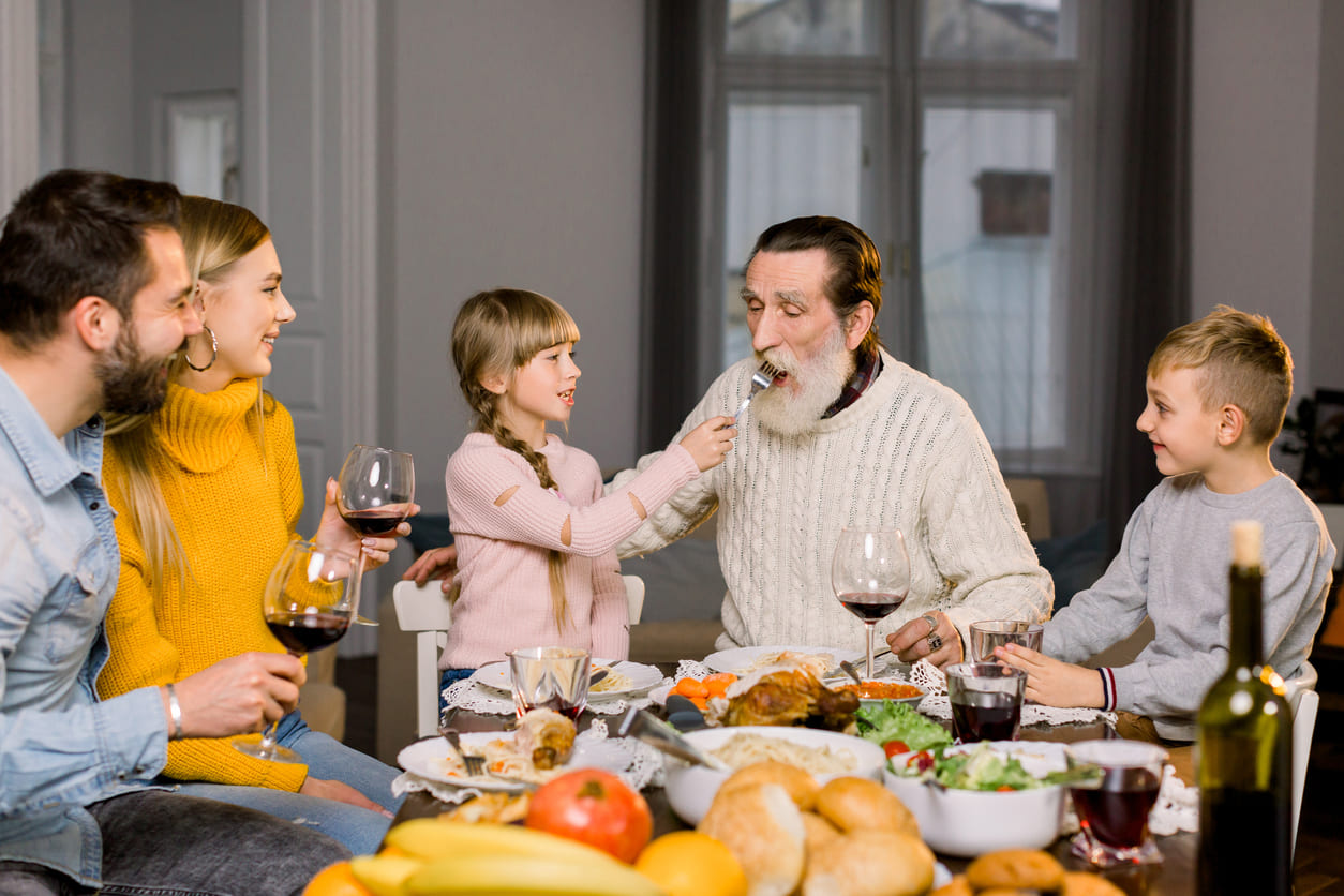 A family joyfully shares a meal together, celebrating with laughter and togetherness.