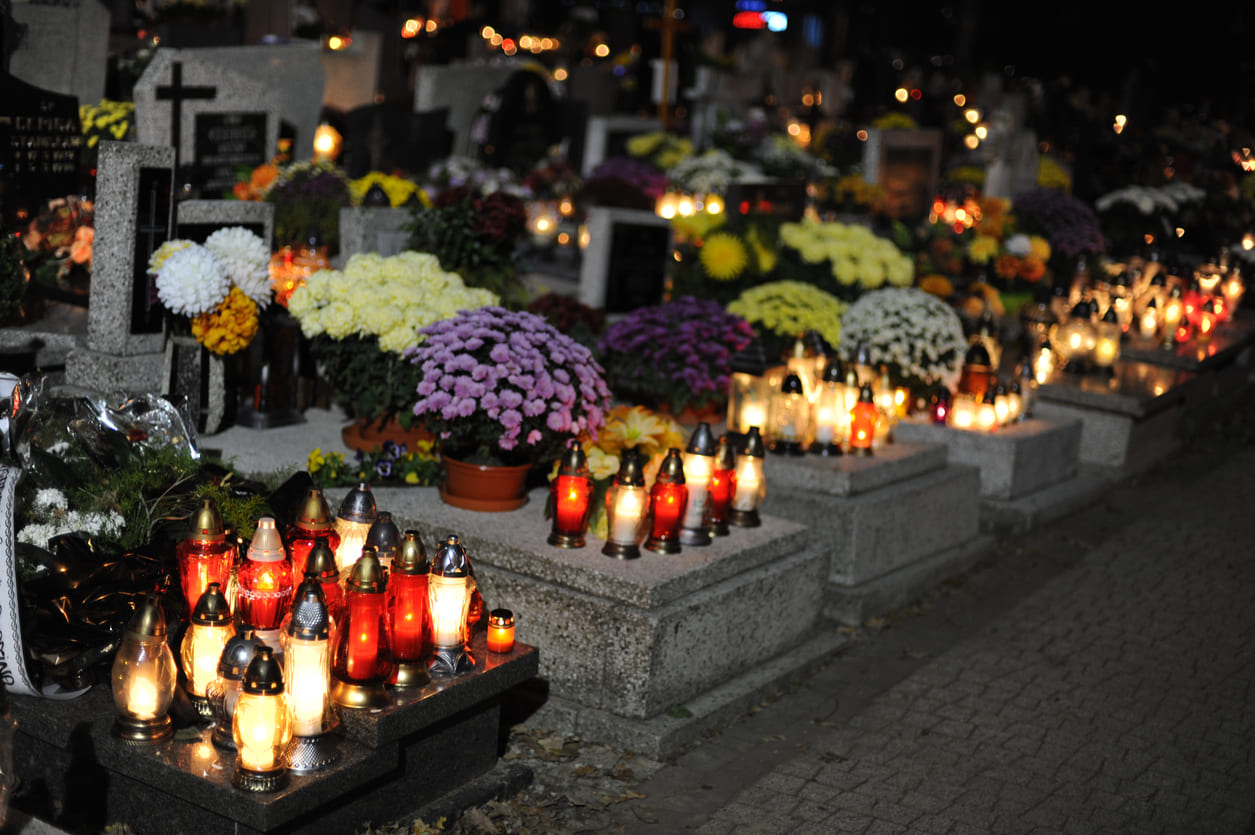 Graves decorated with candles and flowers in remembrance for All Saints' Day.