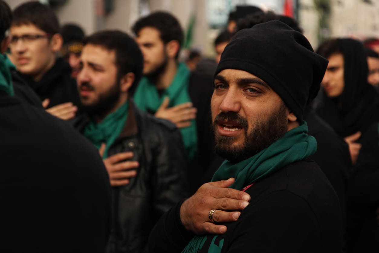 Shia Muslims solemnly participate in an Ashura procession, expressing deep sorrow and remembrance for Imam Hussein's martyrdom.