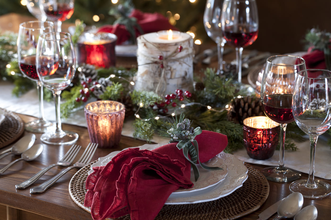 A festive Christmas table adorned with candles, decorations, and wine, prepared for a holiday feast.