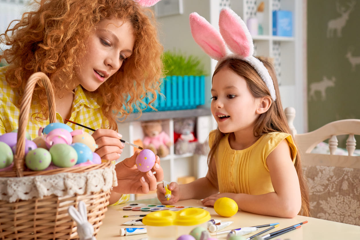 A mother and daughter joyfully paint Easter eggs together, capturing the festive spirit of Easter Monday.