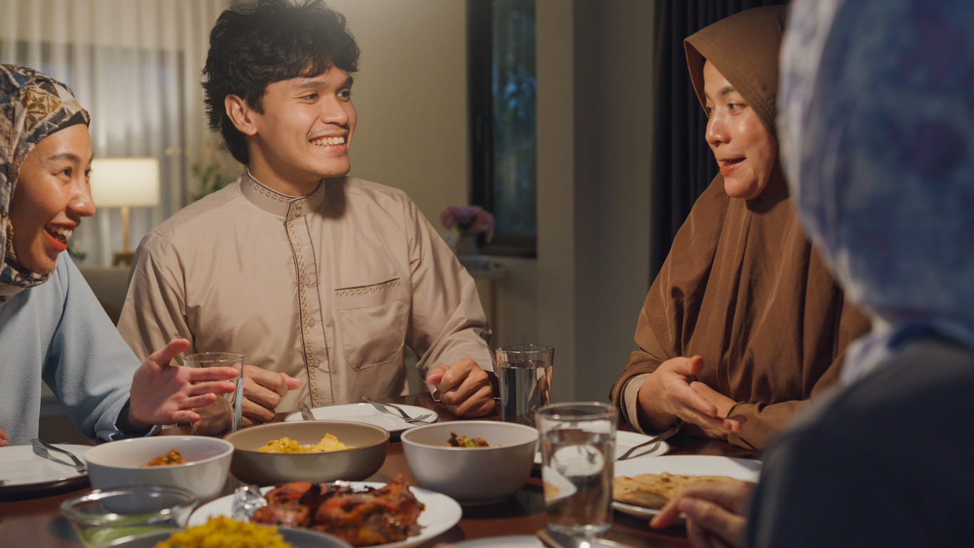 A family gathers with smiles, sharing a festive meal in celebration of Eid al-Fitr.