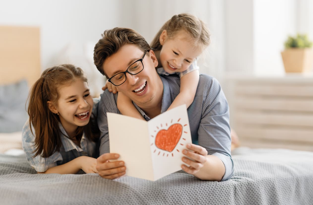 A father reads a heartfelt card with his smiling children, capturing the joy of Father's Day.