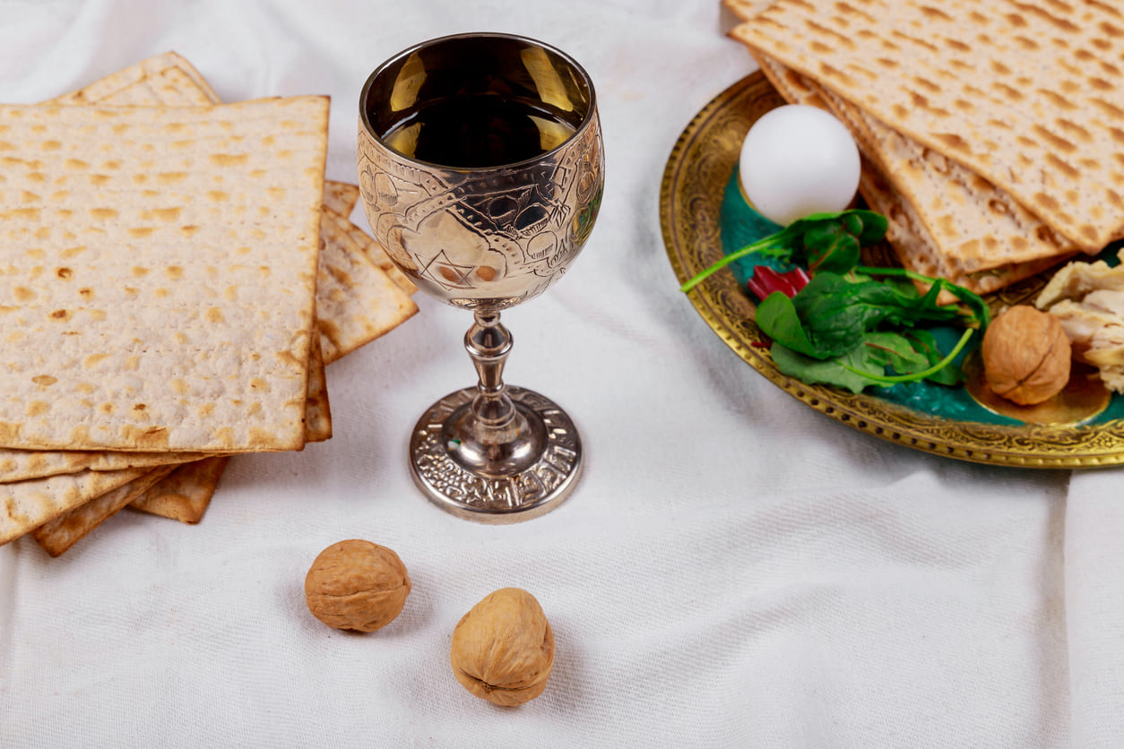 A Passover Seder table with matzah, a silver cup, and symbolic foods representing the Exodus story.