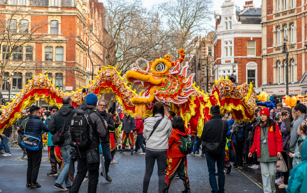 A colorful dragon dance winds through a bustling street, drawing an enthusiastic crowd in celebration of Lunar New Year.