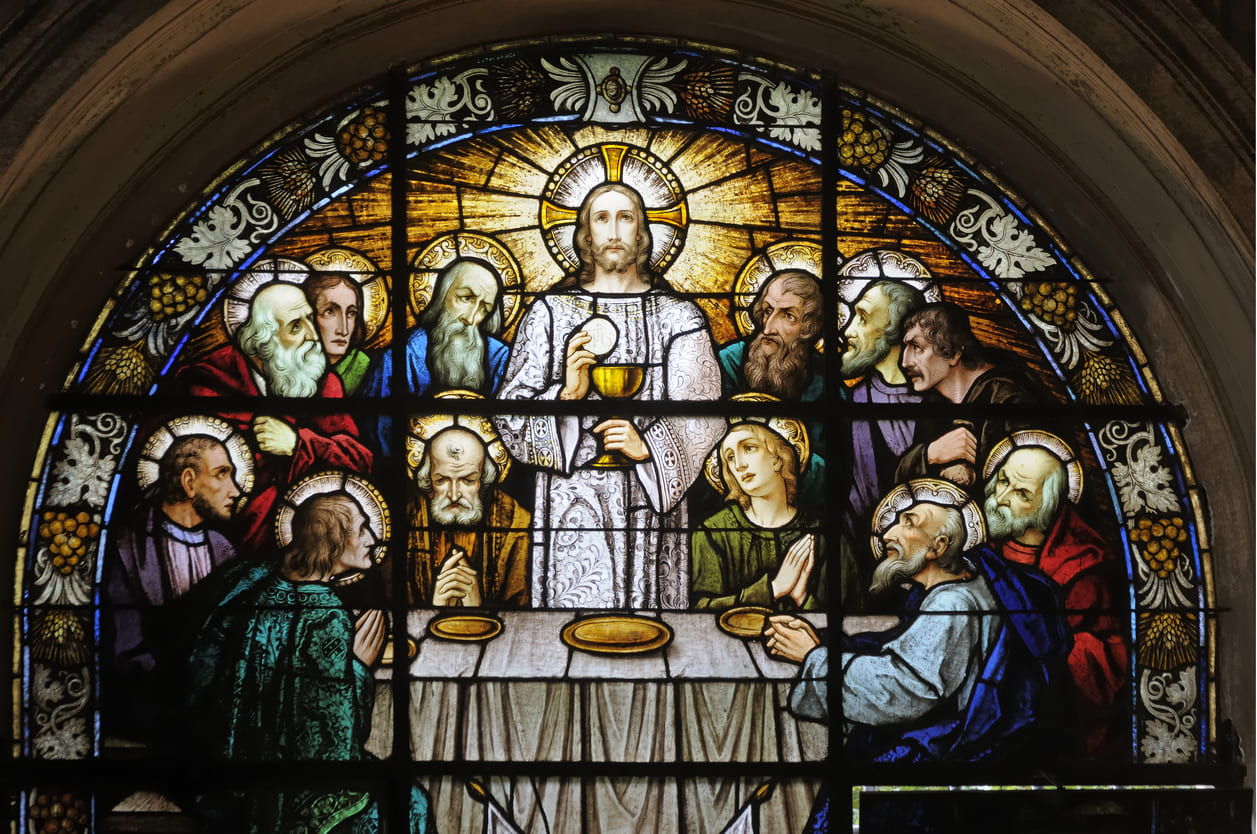 A stained glass window portrays Jesus and his disciples at the Last Supper, illustrating the solemnity of Maundy Thursday.