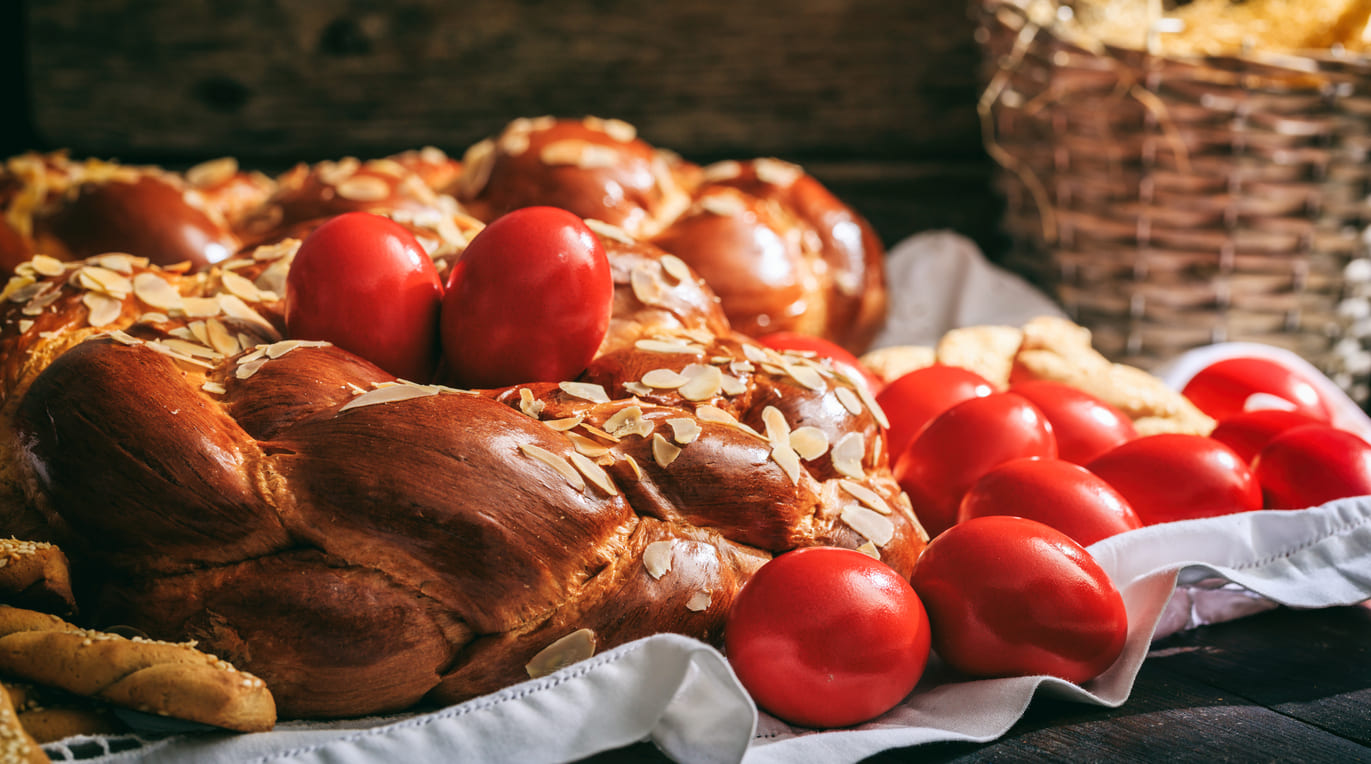 Red-dyed eggs and almond-topped tsoureki bread, traditional symbols of Orthodox Easter celebrations.