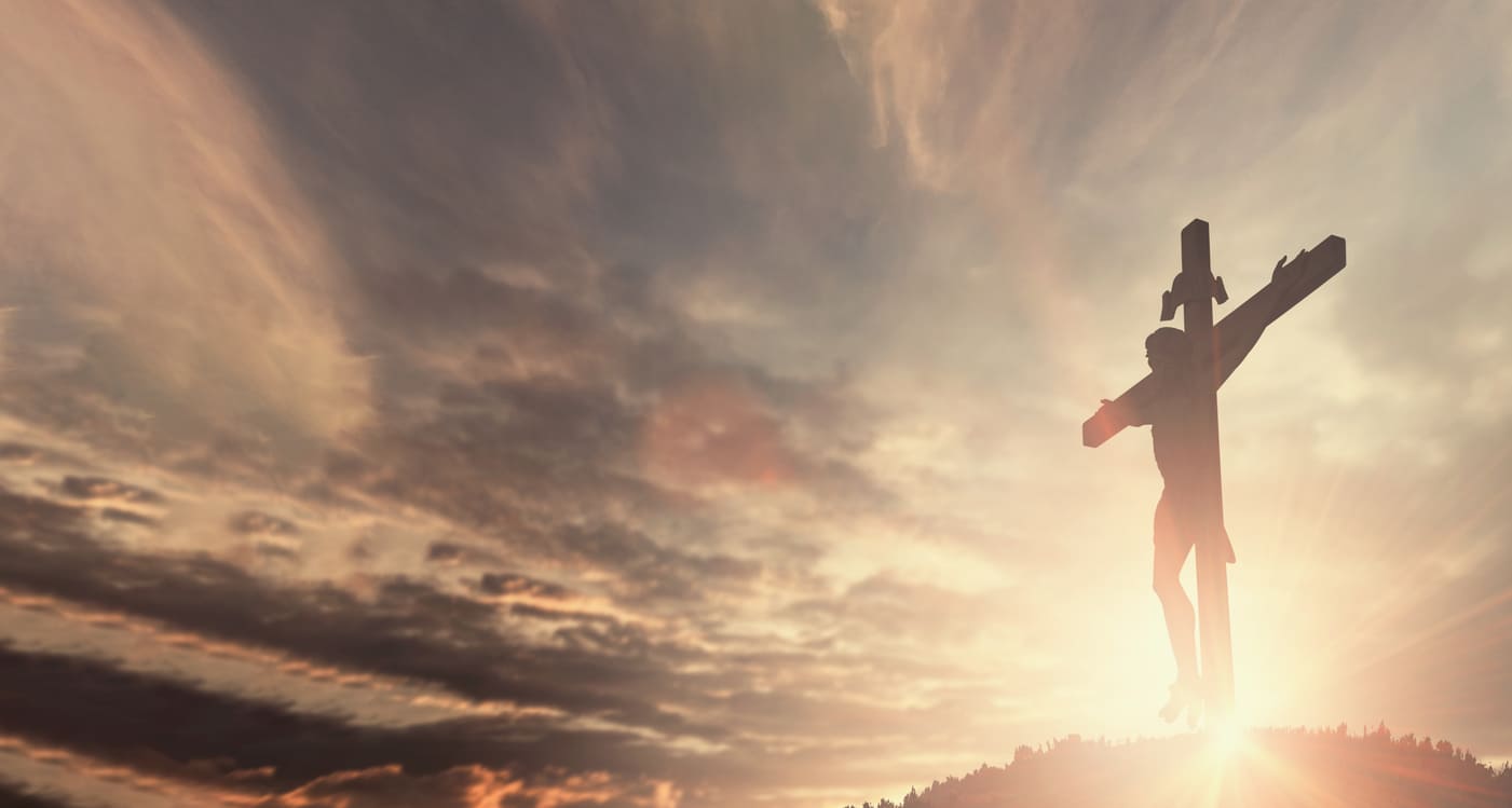 Jesus on the cross, silhouetted against a bright, dramatic sunset.