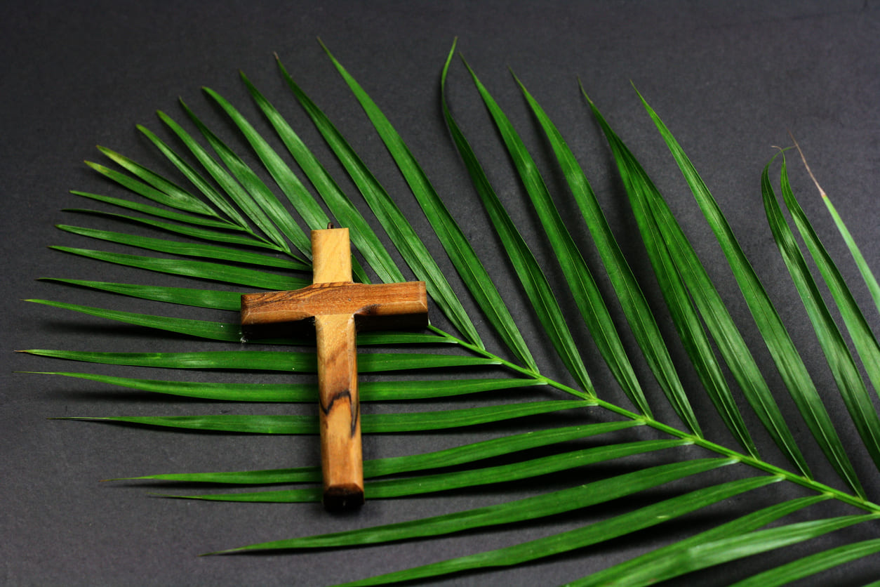 A wooden cross placed on palm leaves, symbolizing the significance of Palm Sunday in the Christian tradition.