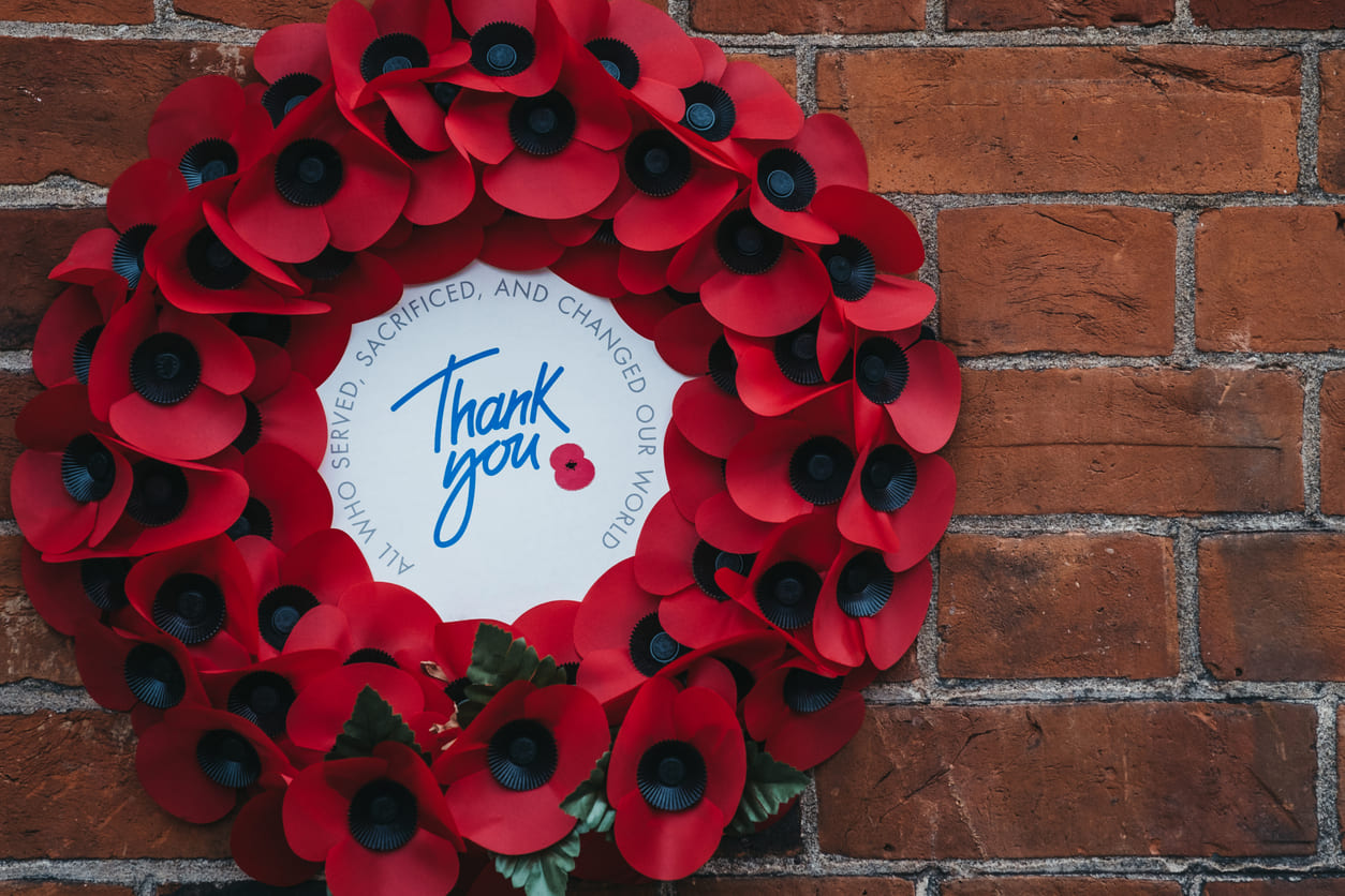 A wreath of red poppies with a message of gratitude, symbolizing remembrance and honoring those who served and sacrificed.