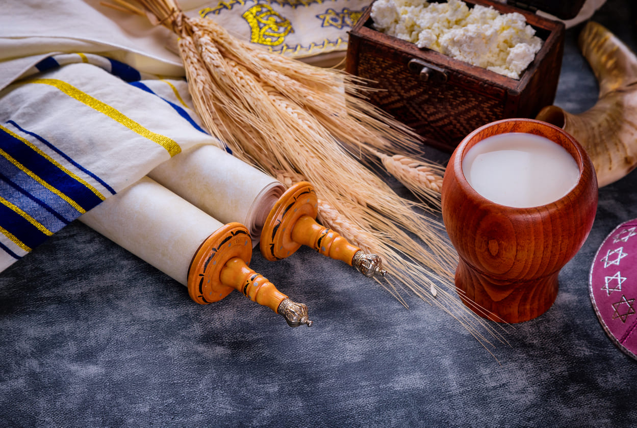 A symbolic display for Shavuot, featuring Torah scrolls, wheat, and dairy products during the festival.