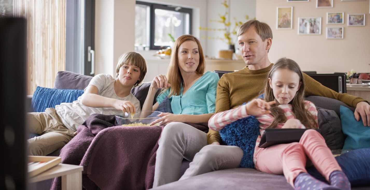 A family relaxes on a sofa, spending quality time together during the Spring Bank Holiday.