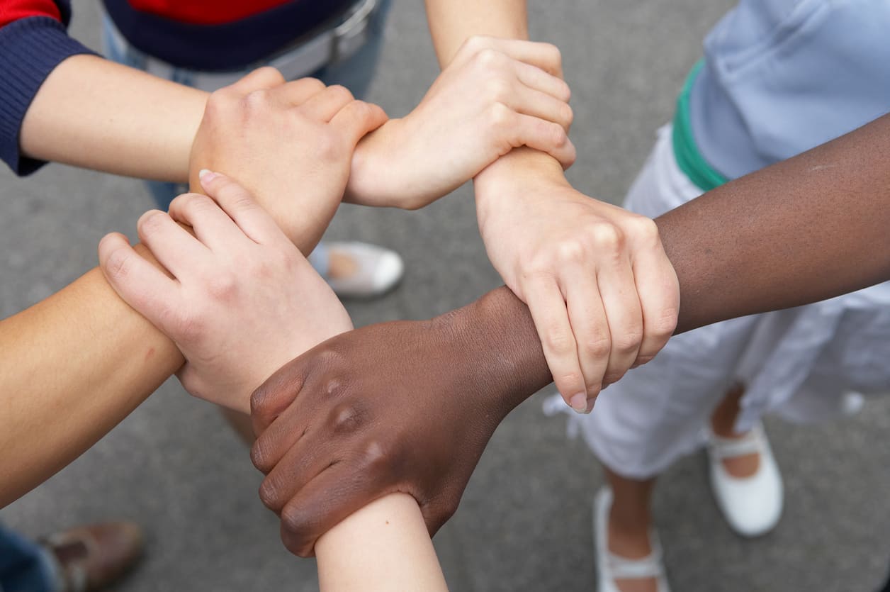 Hands of different skin tones clasped together, symbolizing unity, diversity, and solidarity.