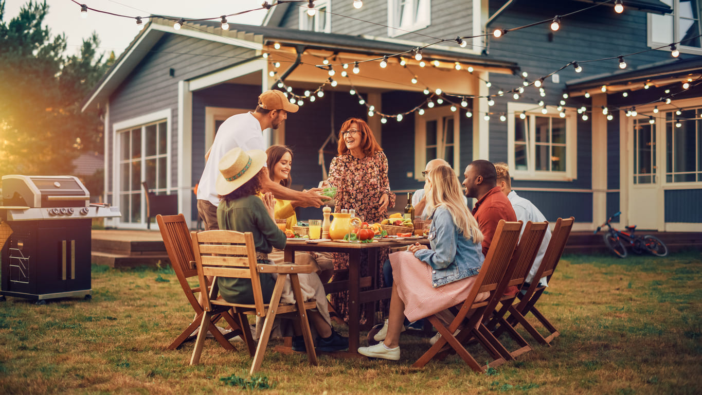 Friends and family enjoying a summer gathering with food and laughter outdoors, celebrating the Summer Bank Holiday in a relaxed and festive atmosphere.