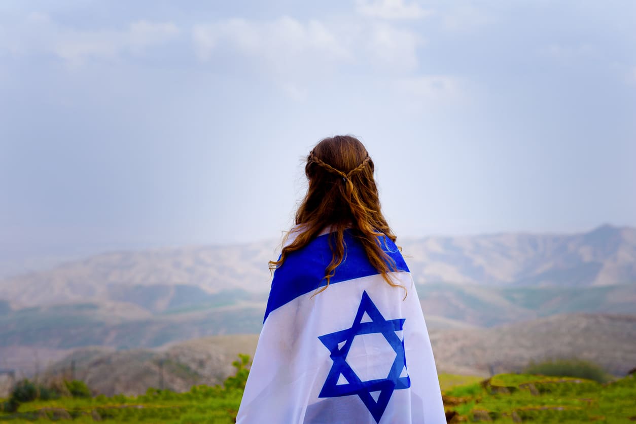 The Israeli flag draped over woman's shoulders symbolizes pride and celebration of Yom Ha'atzmaut.