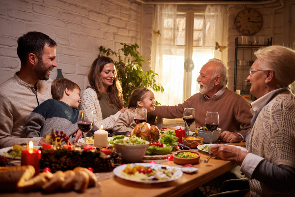 Family happily gathered around a festive dinner table, enjoying a warm and joyful moment together.