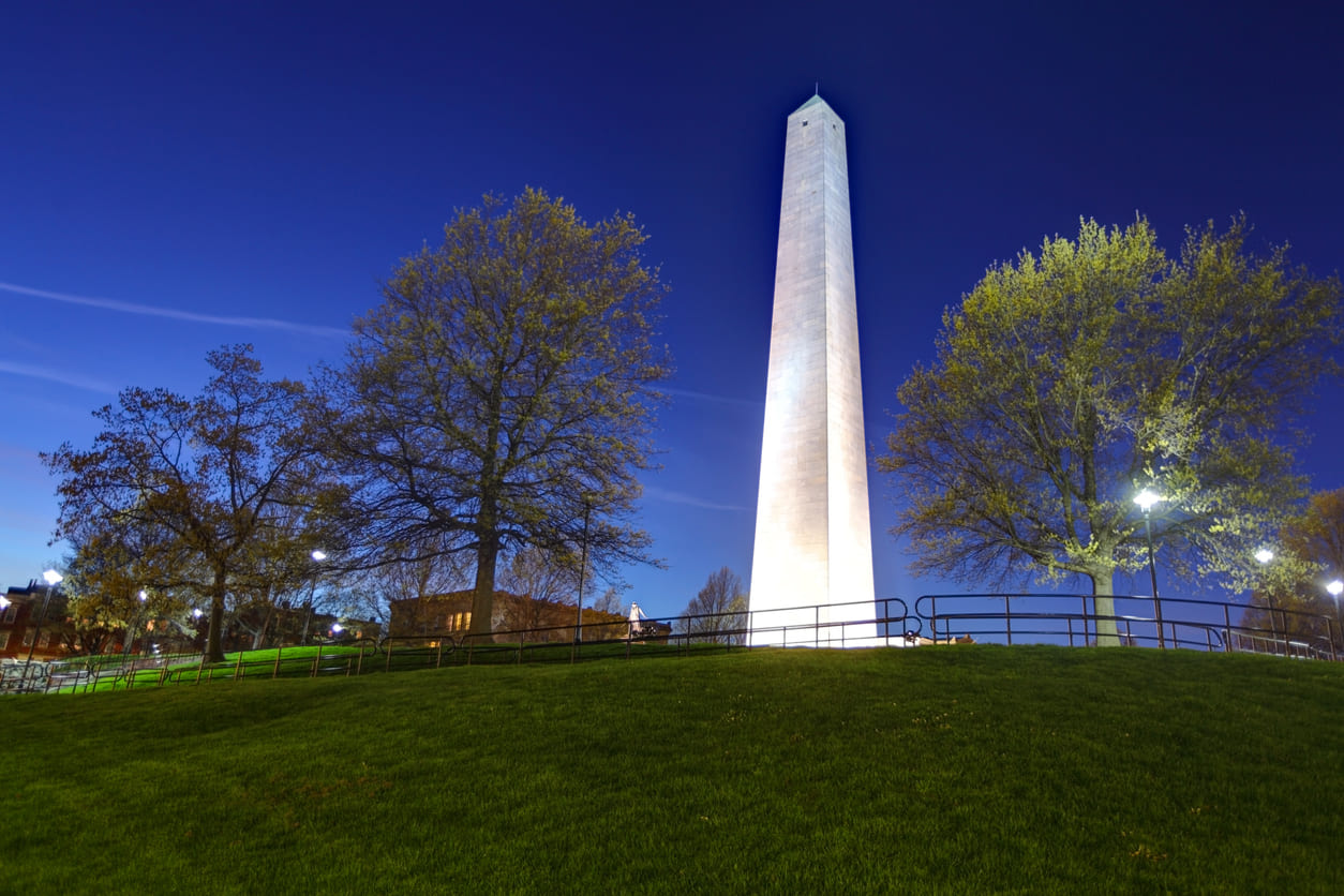 The Bunker Hill Monument, illuminated at night, stands tall in Charlestown, Massachusetts, commemorating the 1775 Battle of Bunker Hill.