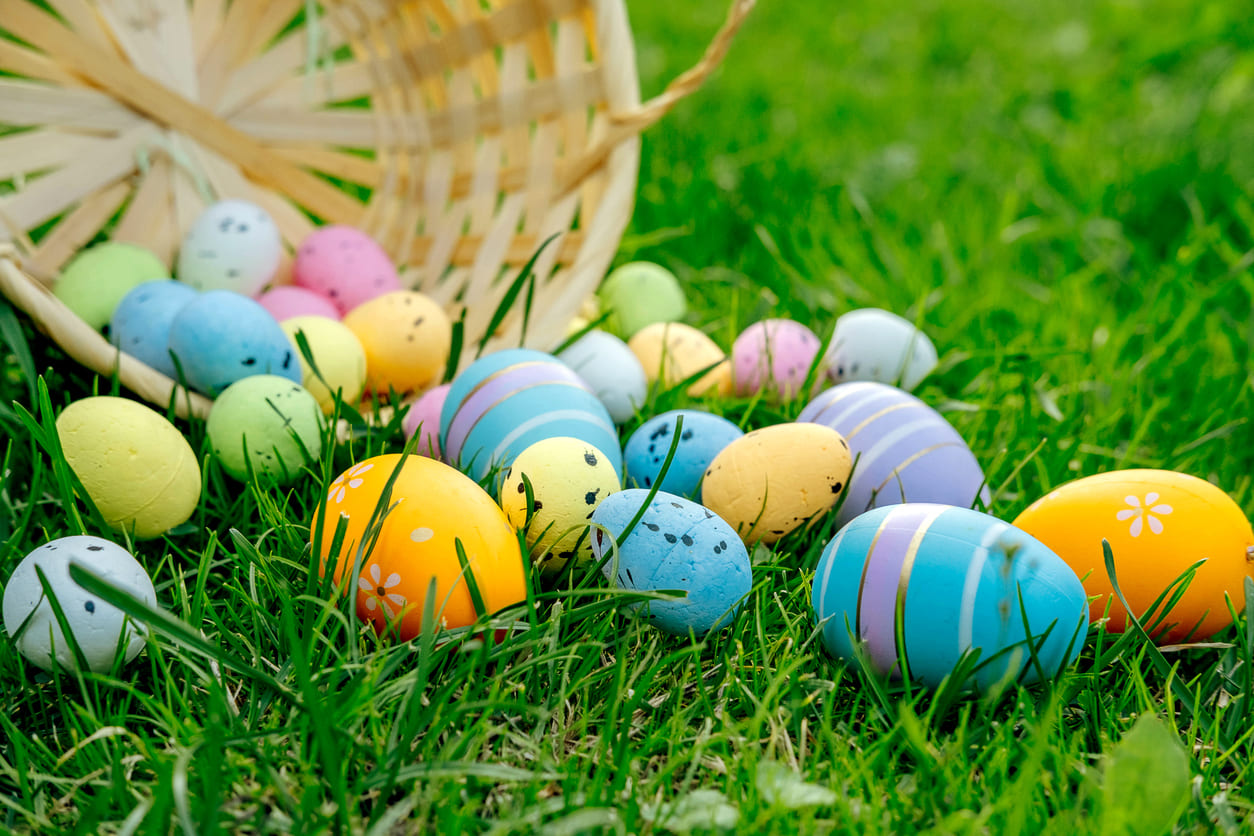 Colorful Easter eggs spill from a wicker basket, symbolizing joy and the tradition of egg rolling on Easter Monday.