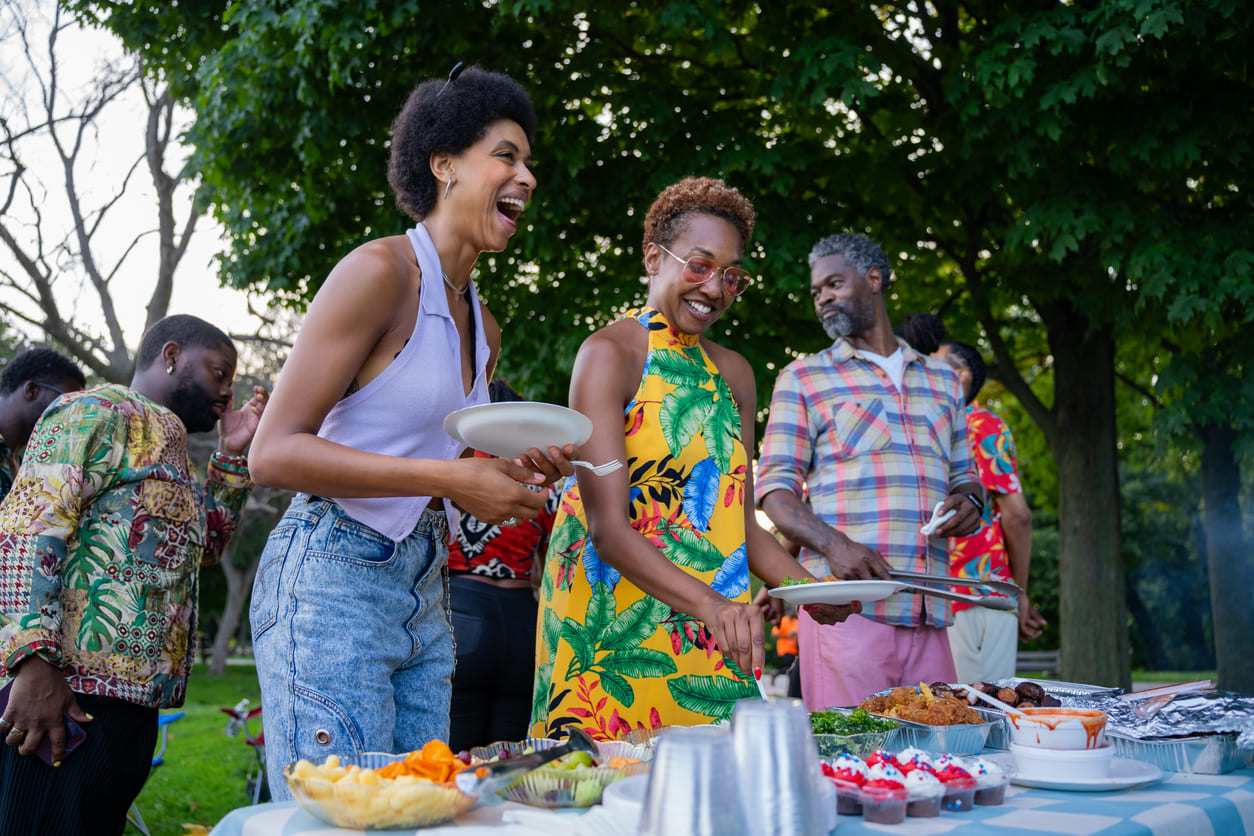 A group of people enjoying an outdoor gathering with food, laughter, and lively conversation.